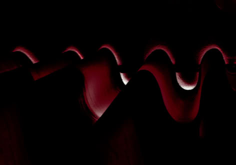 Abstract image with dark red and black wavy patterns and shadows.
